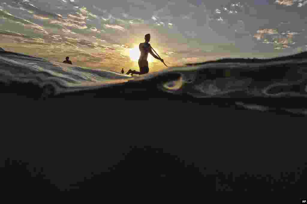 A man floats on a paddle board off Copacabana beach in Rio de Janeiro, Brazil, during a heat wave.