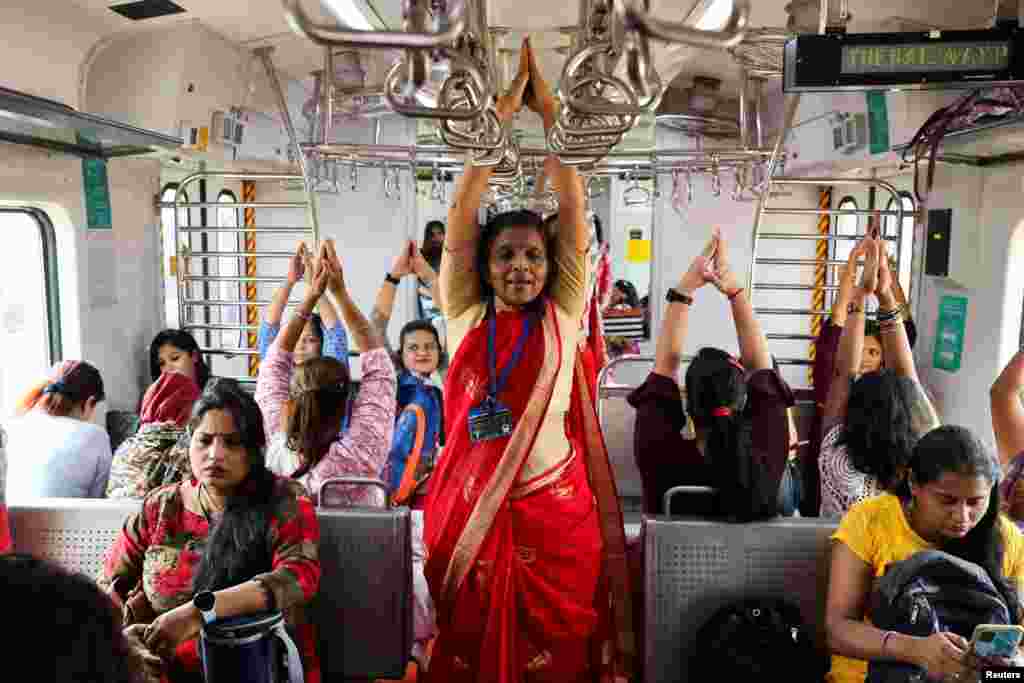 Women practice yoga in a local train on the occasion of International Women's Day in Mumbai, India.