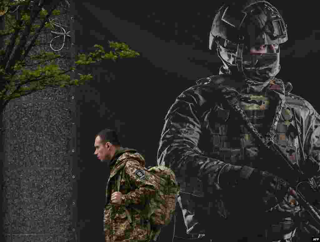 A Ukrainian serviceman walks past a recruiting poster in Kyiv, amid the Russian invasion of Ukraine.