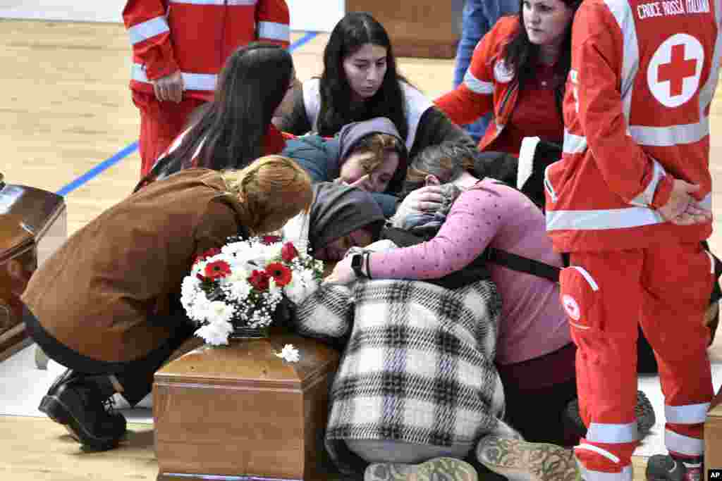 Relatives cry on the coffin of one of the victims of last Sunday's shipwreck at the local sports hall in Crotone, southern Italy. At least 67 people died when their overcrowded wooden boat broke apart in rough water just off a beach in Calabria.