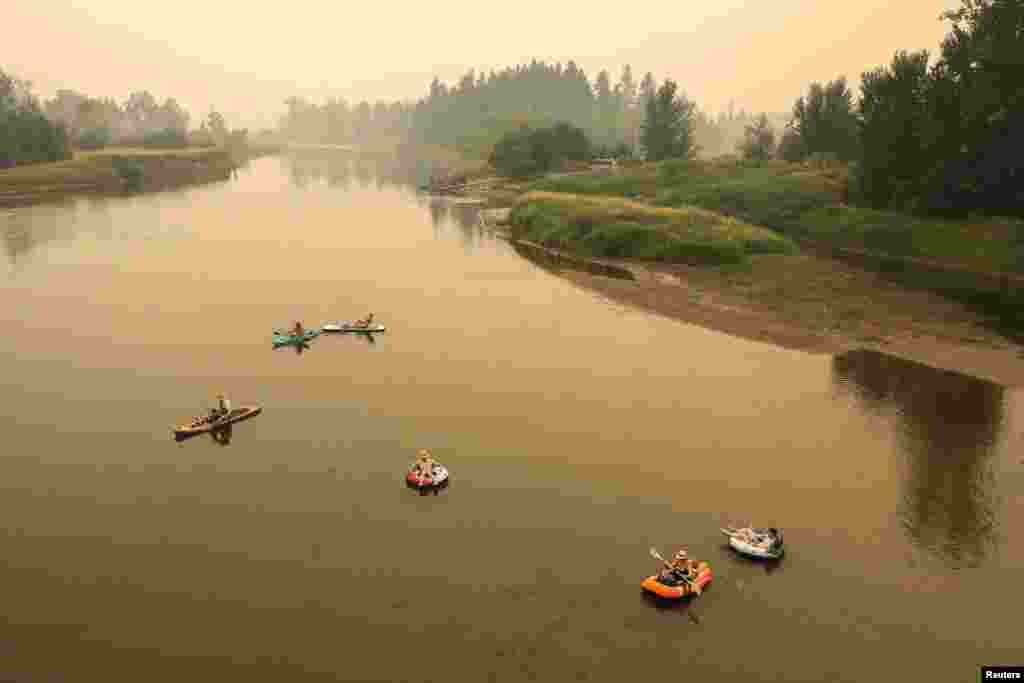 People float down the Shuswap River on rafts and kayaks as a haze from wildfire smoke fills the valley in Enderby, British Columbia, Canada, Aug. 19, 2023.