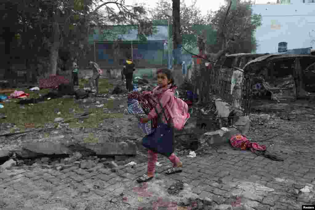 A girl carrying her belongings walks in the area of Al-Ahli hospital where hundreds of Palestinians were killed in a blast that Israeli and Palestinian officials blamed on each other, and where Palestinians who fled their homes were sheltering, in Gaza City. 