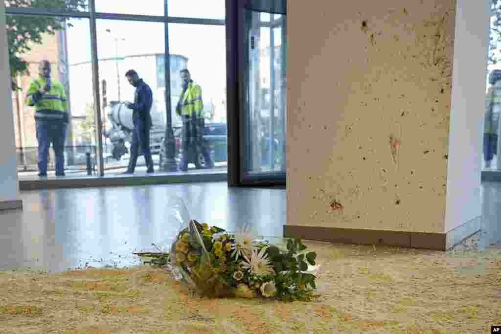 Flowers laid in tribute inside an office building in Brussels, at the scene close to where two Swedish soccer fans were shot by a suspected Tunisian extremist on Monday night. Police in Belgium have shot dead a suspected Tunisian extremist accused of killing two Swedish soccer fans in a brazen attack on a Brussels street before disappearing into the night on Monday.