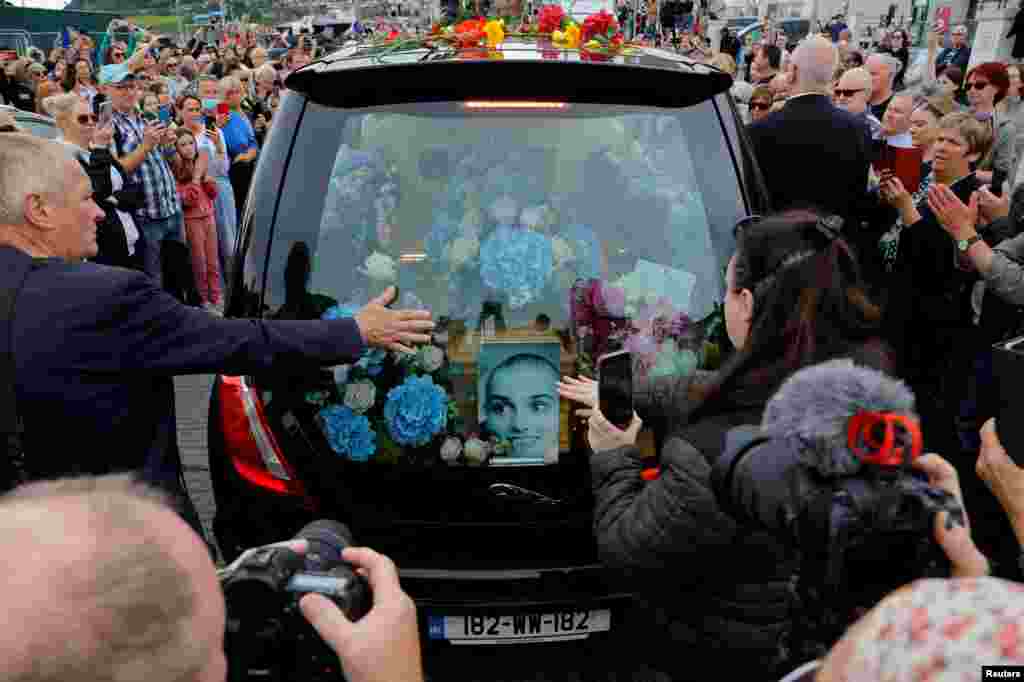 A hearse carrying the coffin of late Irish singer Sinead O'Connor passes by during her funeral procession as fans line the street to say their last goodbye to her, in Bray, Ireland.