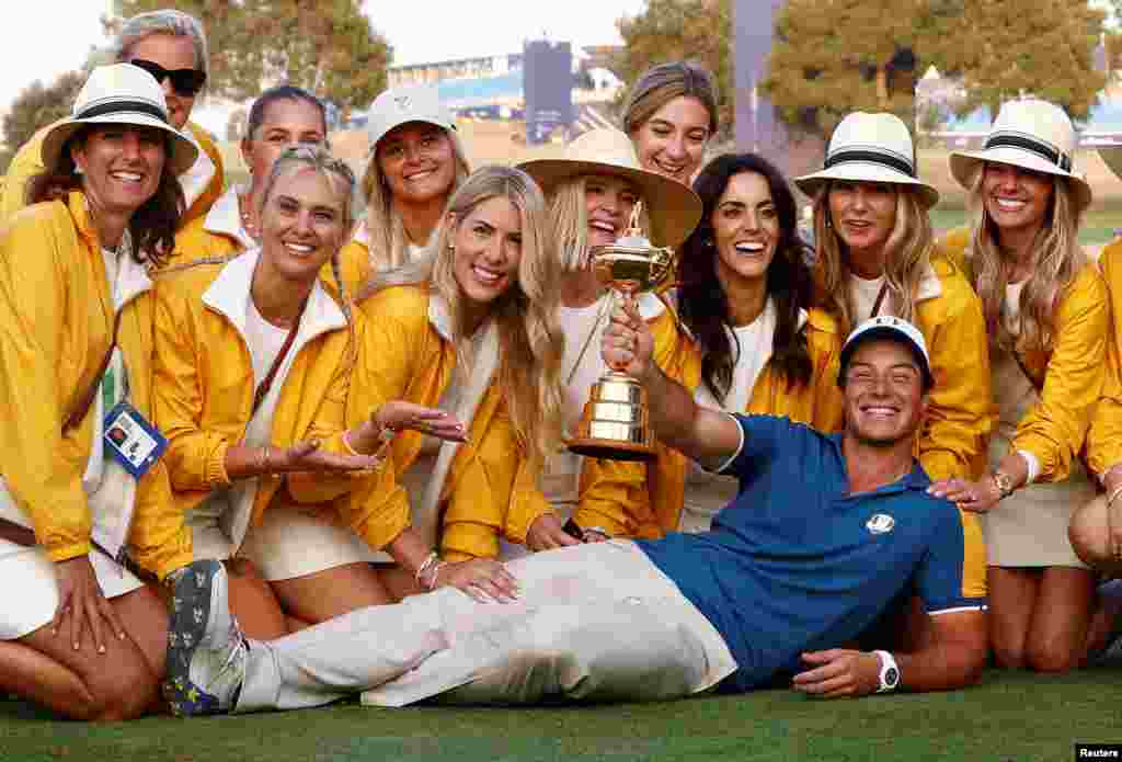 Team Europe's Viktor Hovland poses with the trophy and the partners of his teammates as they celebrate after winning the 2023 Ryder Cup in Rome, Italy, Oct. 1, 2023.