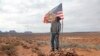 FILE - In this Oct. 25, 2018, photo, Brandon Nez displays his flag near his jewelry stand in Monument Valley, Utah. 