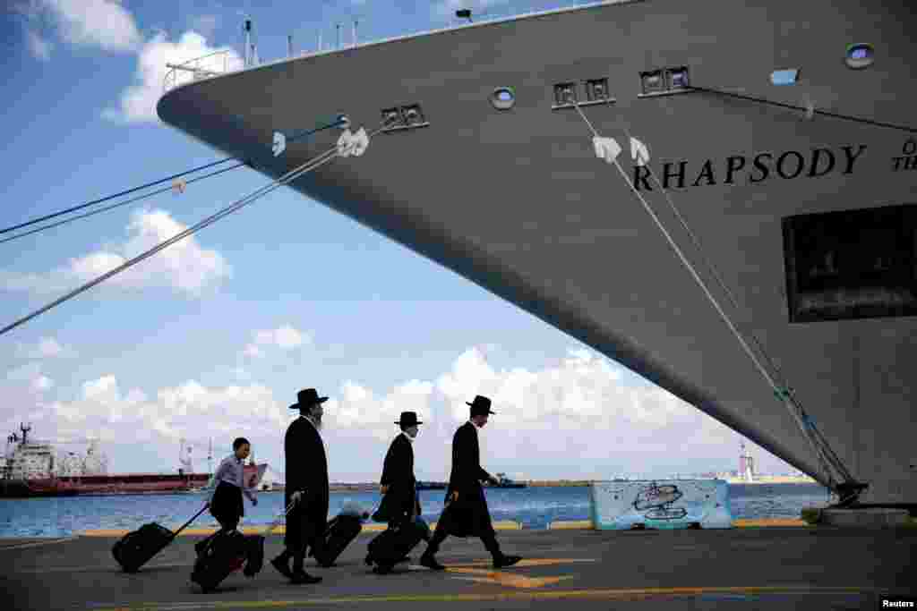 Ultra-Orthodox Jewish people carry their belongings before boarding a ship for U.S. nationals and their immediate family members, as they leave Israel headed for Cyprus, in Haifa, Israel.