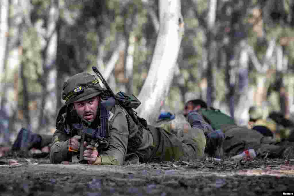 Israeli soldiers take cover after a warning of potential incoming fire from Gaza at the site of the surprise attack launched by Hamas on October 7th during a dance party near Reim, Israel.
