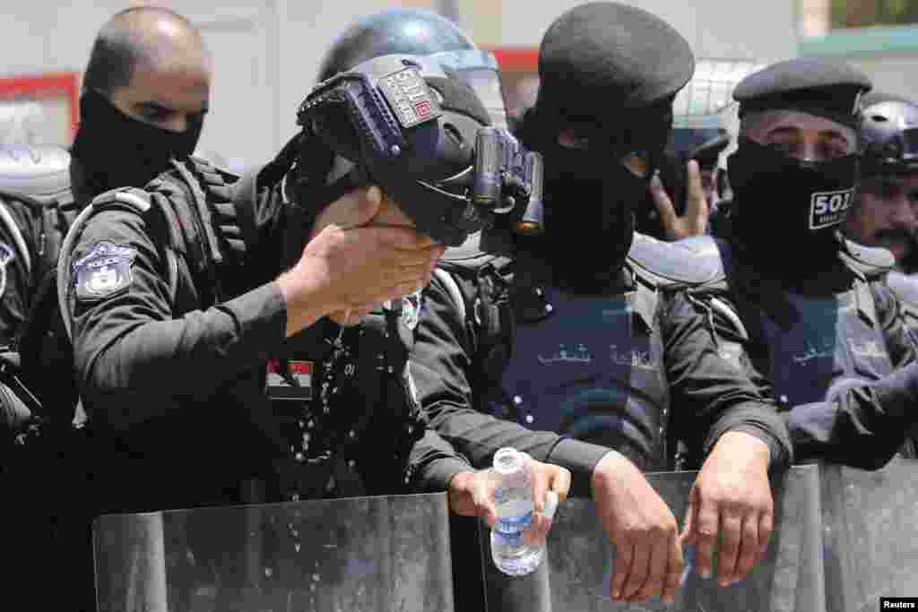 A police officer washes his face as protesters gather near the Turkish Embassy during a demonstration against cutting Iraq's water supply, in Baghdad.