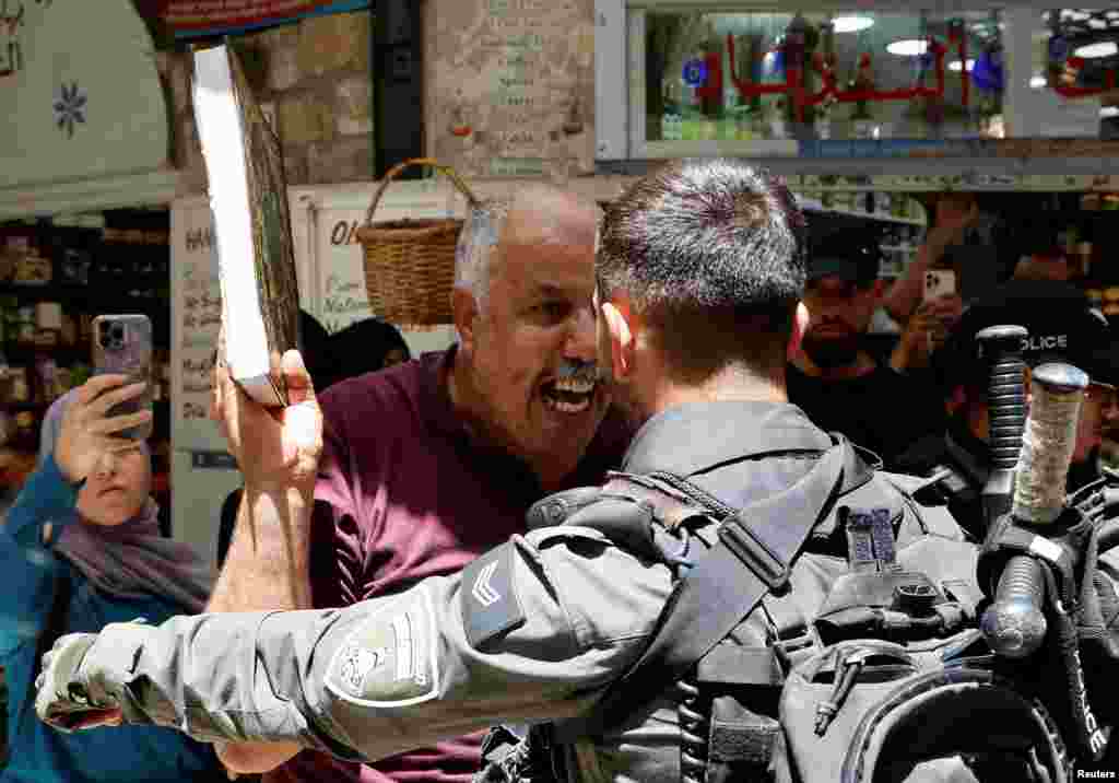 A man holds a copy of Quran as Israeli police blockade the entrance to Al-Aqsa compound following a visit to the site by Israel's hard-right National Security Minister Itamar Ben-Gvir, in Jerusalem's Old City.