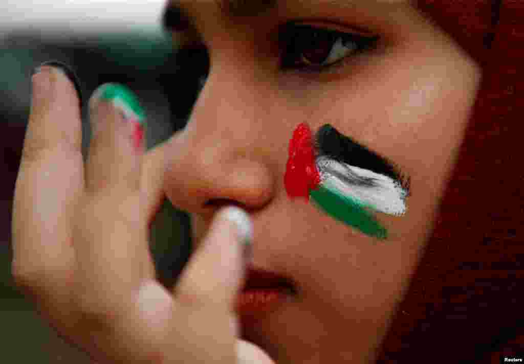 A woman with the colors of the Palestinian flag painted on her cheek takes part in a solidarity gathering in support of Palestinians in Kuala Lumpur, Malaysia.