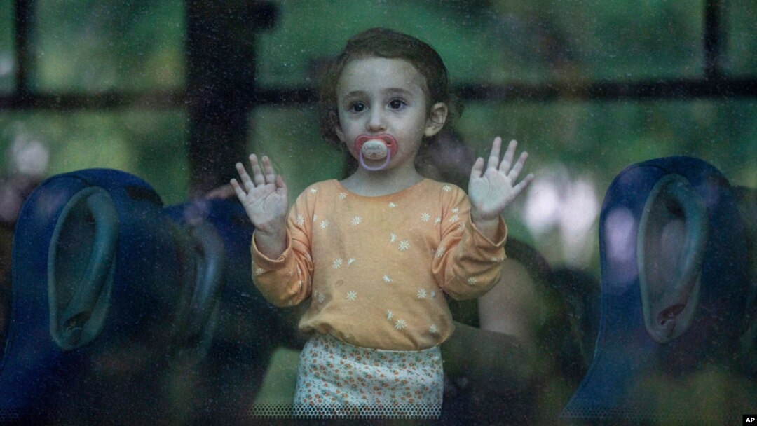 A young girl looks through a bus window as her family departs the northern Israeli city of Kiryat Shmona, Israel, Oct. 20, 2023.