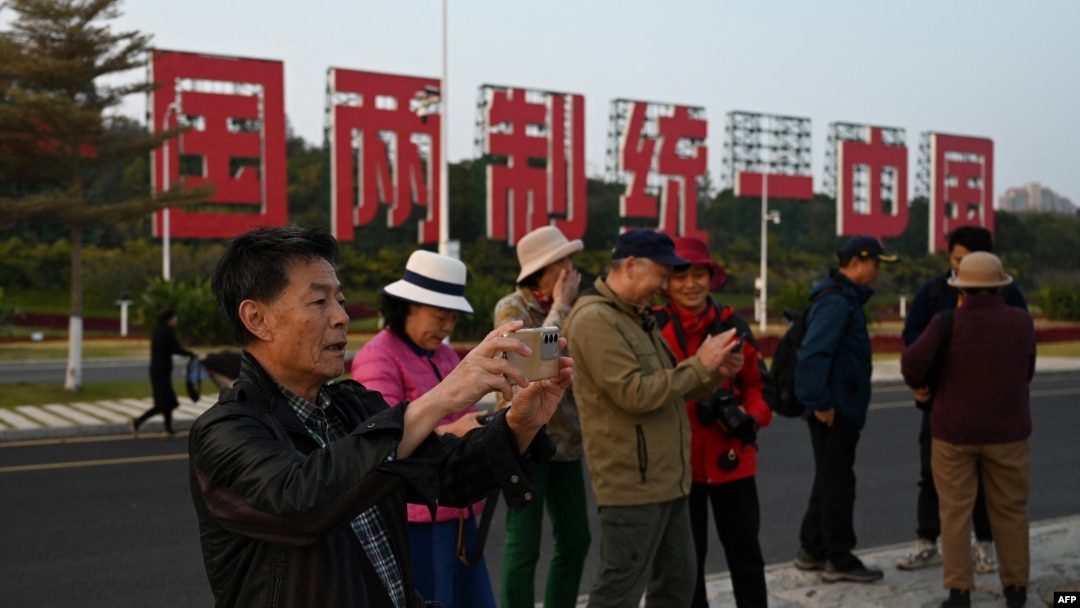 中國福建廈門豎立起一個台灣金門島可以看到的「一國兩制統一中國」的大型標語牌，旅遊者在前拍照。（2024年1月12日）