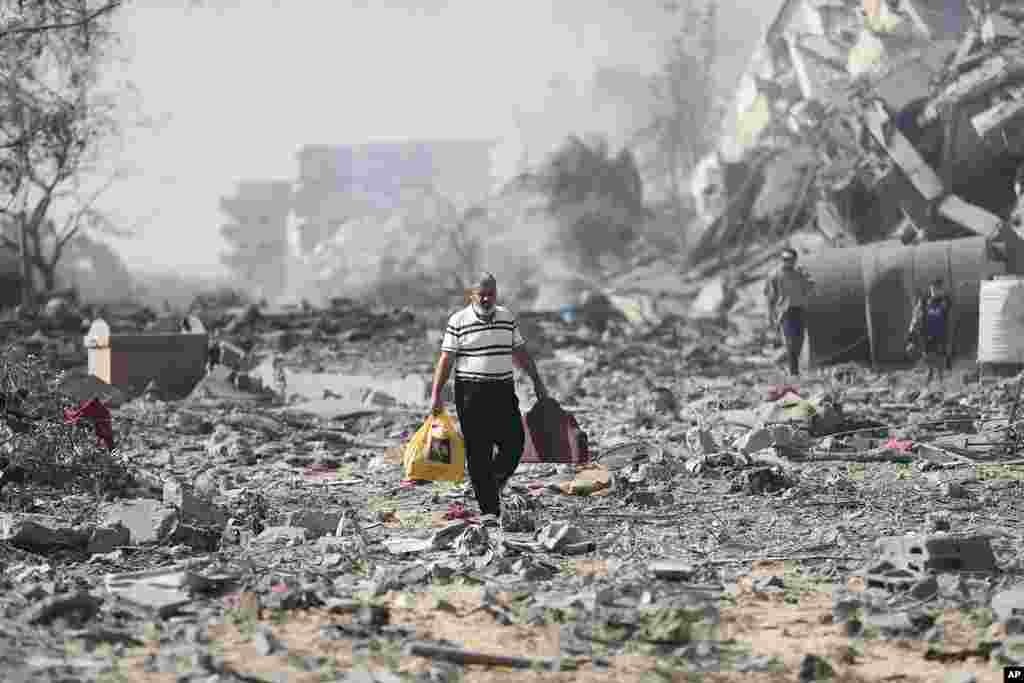 Palestinians walk by the buildings destroyed in the Israeli bombardment on al-Zahra, on the outskirts of Gaza City.