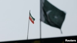 Bendera Iran terlihat di gedung konsulatnya di kota Karachi, Pakistan, sementara bendera Pakistan tampak di latar depan, 18 Januari 2024.