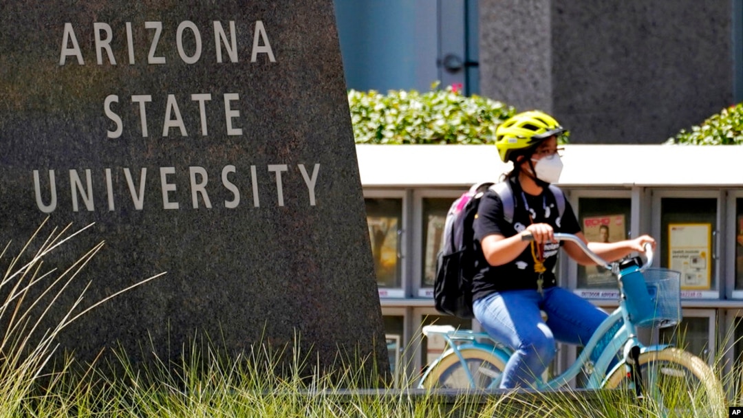 FILE - A cyclist crosses an intersection on the campus of Arizona State University on Sept. 1, 2020, in Tempe, Ariz.