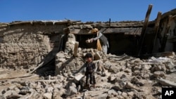 Seorang pria membersihkan puing-puing setelah gempa bumi mengguncang desa Gayan, provinsi Paktika, Afghanistan, Jumat, 24 Juni 2022. (AP/Ebrahim Nooroozi)