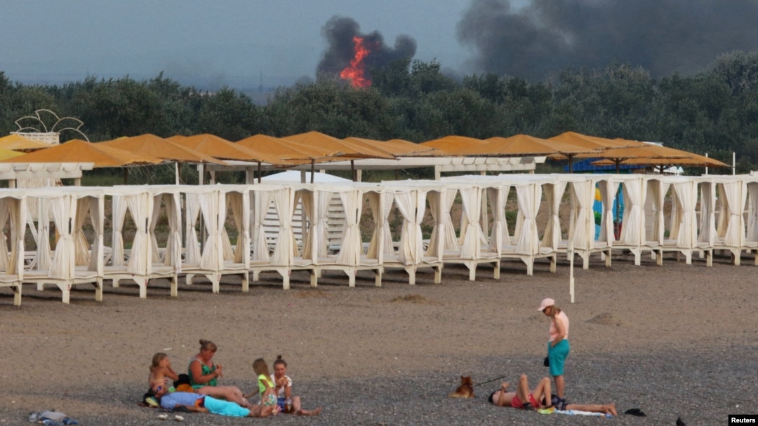 ARHIVA - Ljudi se odmaraju na plaži dok se dim i plamen uzdižu posle eksplozije u ruskoj vojnoj vazduhoplovnoj bazi u Novofedorivki na Krimu, 9. avgusta 2022.