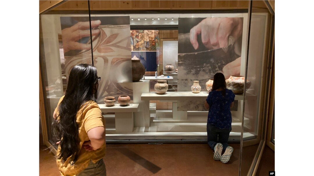 Elysia Poon, director of the Indian Arts Research Center in New Mexico, at left, oversees finishing touches on a community-curated exhibition of Native American pottery from the Pueblo Indian region of the U.S. Southwest on July 28, 2022, at the Museum of Indian Arts and Culture in Santa Fe, N.M. (AP Photo/Morgan Lee)