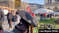 Beskućnik zedi ispred katedrale Noterdam u Parizu. Život je postao teži za Evropljane nakon početka rata u Ukrajini.