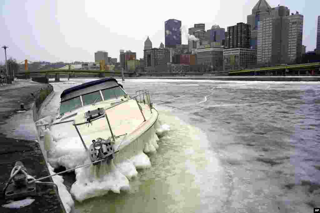 A boat lies partially submerged, surrounded by ice in the Allegheny River in downtown Pittsburgh, Pennsylvania, Dec. 26, 2022.