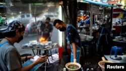 Sejumlah pedagang jajanan kaki lima tampak mengenakan masker sebagai proteksi melawan penyebaran COVID-19 ketika berjualan di area pecinan di Bangkok, Thailand, pada 17 Maret 2022. (Foto: Reuters/Athit Perawongmetha)