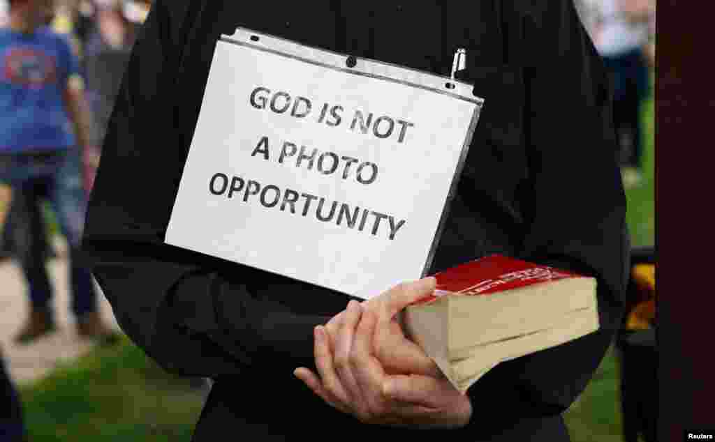 A priest holds a bible and a sign reading "God Is Not A Photo Opportunity" as President Donald Trump's motorcade passes on the way to the nearby Saint John Paul II National Shrine in Washington, D.C., while protests continue against the death of George Floyd in Minneapolis police custody.