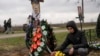 ARCHIVO - Yura Nechyporenko, de 14 años, coloca un chocolate en la tumba de su padre Ruslan Nechyporenko en el cementerio de Bucha, en las afueras de Kiev, Ucrania, el 21 de abril de 2022.