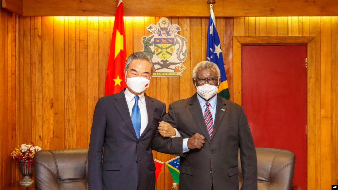 In this photo released by Xinhua News Agency, Solomon Islands Prime Minister Manasseh Sogavare locks arms with visiting Chinese Foreign Minister Wang Yi in Honiara, Solomon Islands, May 26, 2022. 