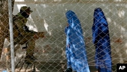 Seorang tentara Taliban berjaga-jaga ketika dua perempuan memasuki kantor paspor pemerintah, di Kabul, Afghanistan, 27 April 2022. (Foto: AP)
