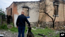 Eduard Zelenskyy acaricia a su perro en su casa destruida por los ataques en Potashnya, en las afueras de Kyiv, Ucrania, el 31 de mayo de 2022. Después de escapar de la guerra, Zelenskyy regresó a su comunidad y descubrió que no tiene hogar.