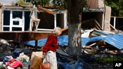 Una mujer camina a través de un edificio destruido en Mariupol, territorio controlado por el gobierno de la República Popular de Donetsk, en el este de Ucrania, el 27 de mayo de 2022.