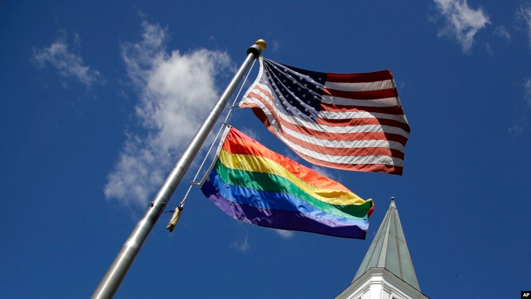 FILE - A gay pride rainbow flag flies with the US flag in front of the Asbury United Methodist Church in Prairie Village, Kan., on April 19, 2019.