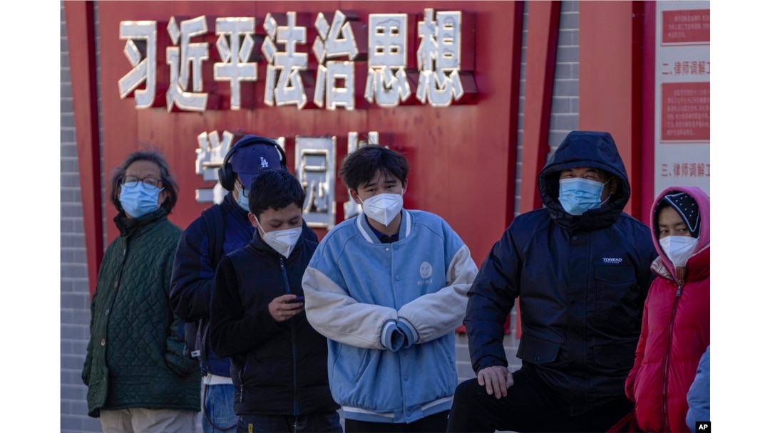 北京市民在宣傳習近平思想的標語牆前排隊等候進行核算檢測。 (2022年12月5日)