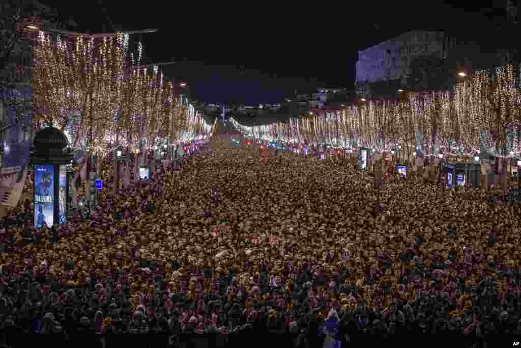 Revelers watch a sound and light show projected on the Arc de Triomphe as they celebrate the New Year on the Champs Elysees in Paris, France, Dec. 31, 2022.