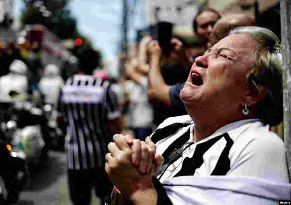 A mourner reacts as the casket of Brazilian soccer legend Pele is transported to the Santos' Memorial Cemetery during his funeral procession in Santos.