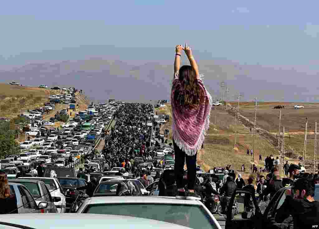 This UGC image posted on Twitter reportedly on Oct. 26, 2022 shows an unveiled woman standing on top of a vehicle as thousands make their way towards Aichi cemetery in Saqez, Mahsa Amini's home town in the western Iranian province of Kurdistan, to mark 40 days since her death, defying heightened security measures as part of a bloody crackdown on women-led protests.