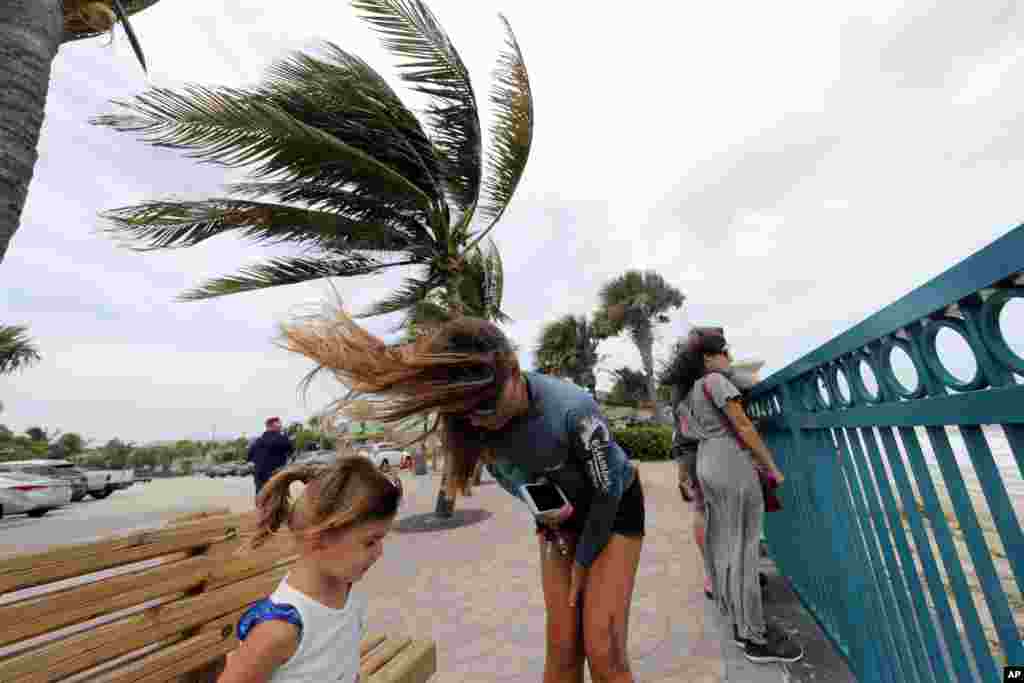 El Centro Nacional de Huracanes (NHC) informó que aunque el debilitamiento gradual es previsible, se espera que Dorian siga siendo un poderoso huracán durante los próximos días. En la foto, una mujer y su hija junto a otras personas en el malecón de Vero Beach, en Florida, el 2 de septiembre de 2019. AP/Gerald Herbert.