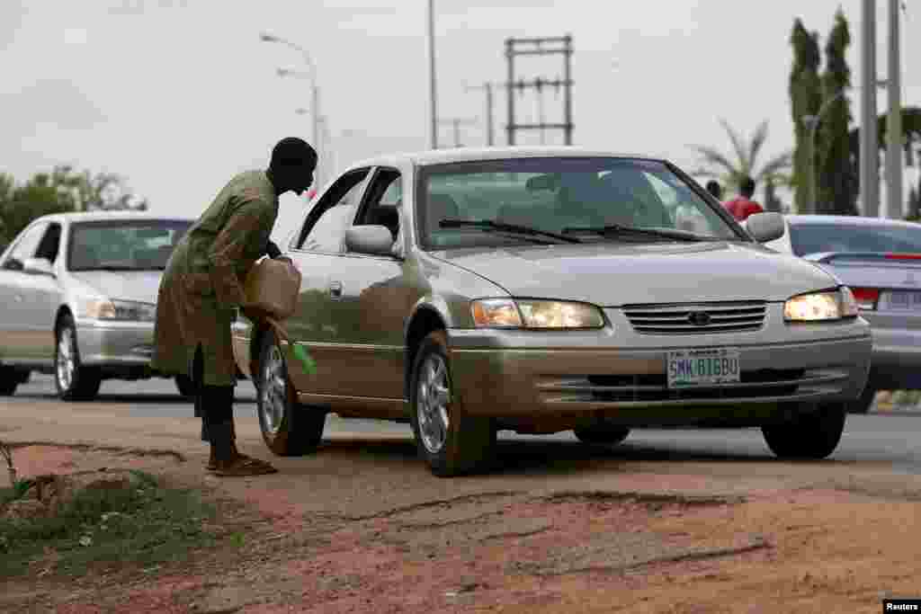 Um homem implora para a gasolina num contentor fora dum posto de gasolina em Abuja, Nigéria 25 de Maio 2015