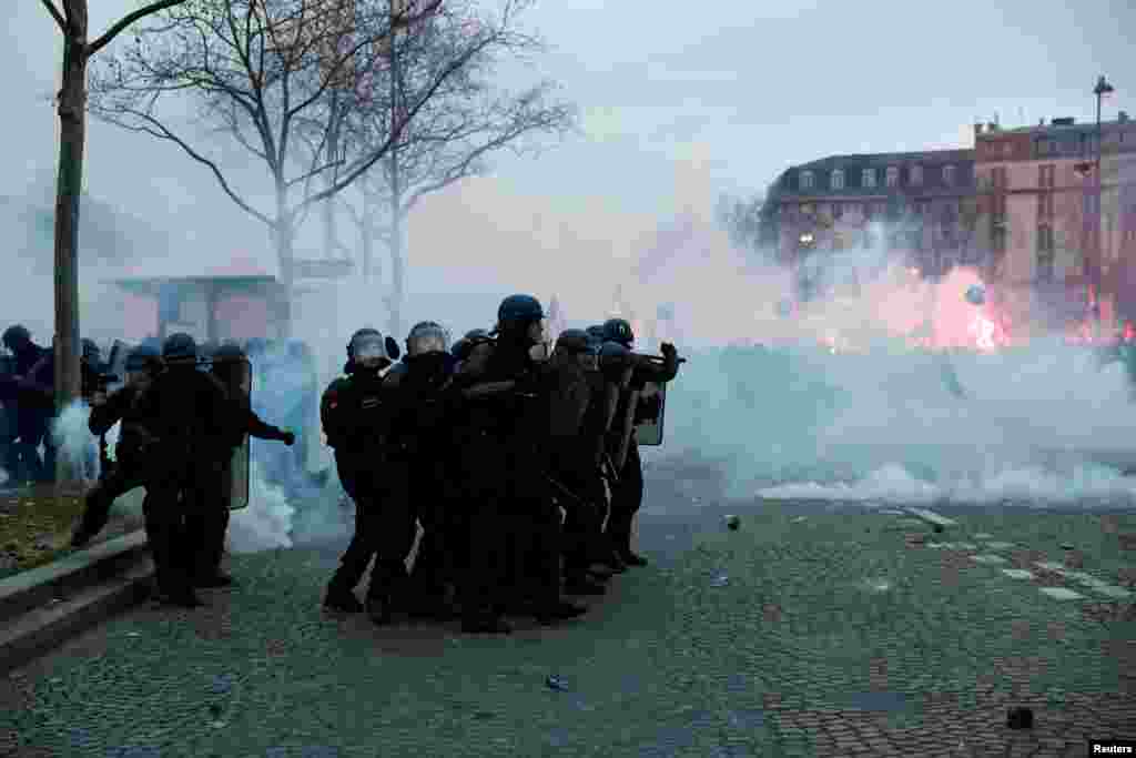 French police hold their position amid clashes with protesters in Paris near the Invalides during a national strike against the French government's pension reform plan.