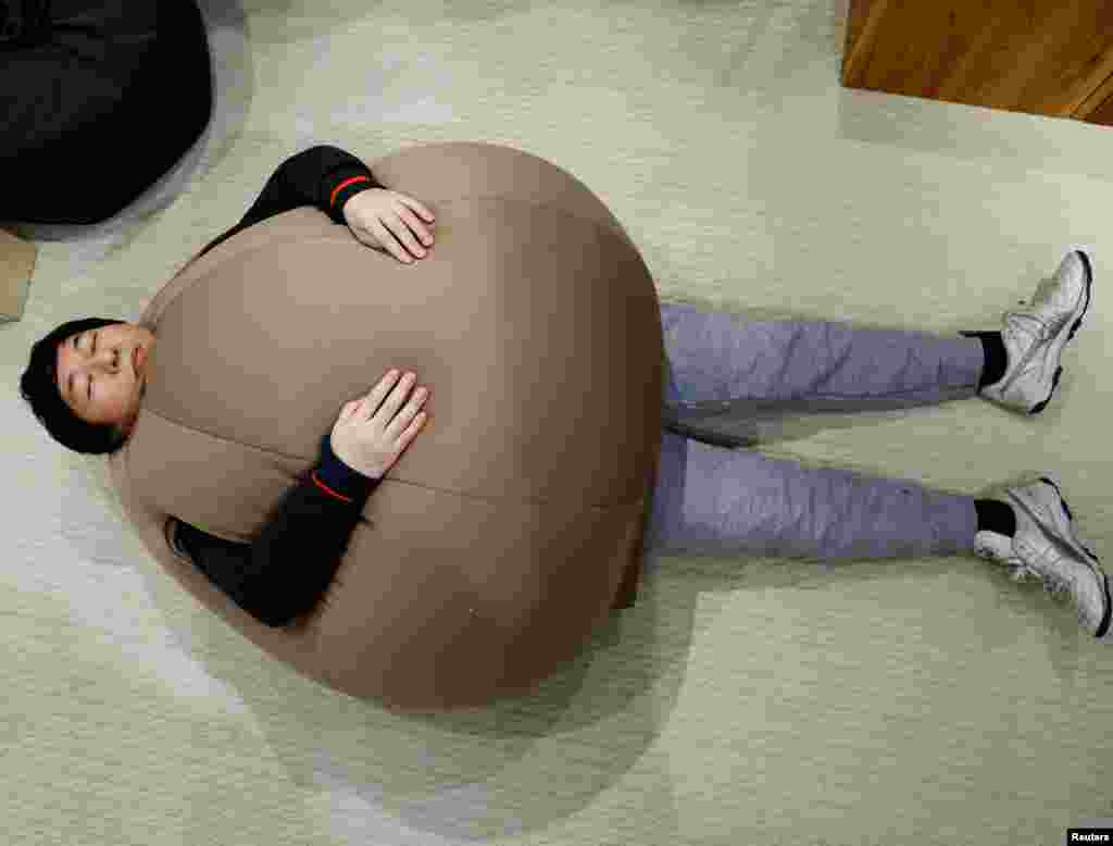 Customer Ryuji Baba tries on the wearable beanbag during a photo opportunity at a pop-up booth of the Shinjuku Marui main department store in Tokyo, Japan, Feb. 6, 2023. While the beanbag's onion-shaped goofy style made it a hit on Japanese social media earlier this month, the main goal was relaxation, according to Shogo Takikawa, a representative of the beanbag's manufacturer, Takikou Sewing. 