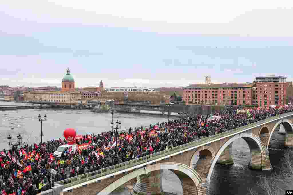 Protesters walk on the Catalans' bridge as they participate in a demonstration on the third day of nationwide rallies against a deeply unpopular pensions overhaul in Toulouse, southwestern France.