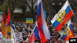 Ljudi sa transparentima na ukrajinskim zastavama (u pozadini) protestuju protiv proruskih demonstracnata koji mašu ruskim zastavama, u Frankfurtu na Majni, istočna Nemačka, 10. aprila 2022.