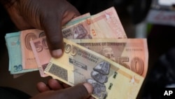 Sarafu ya Zimbabwe isiyo na thamani yeyote na dola ya Marekani katika biashara ya mitaani. 