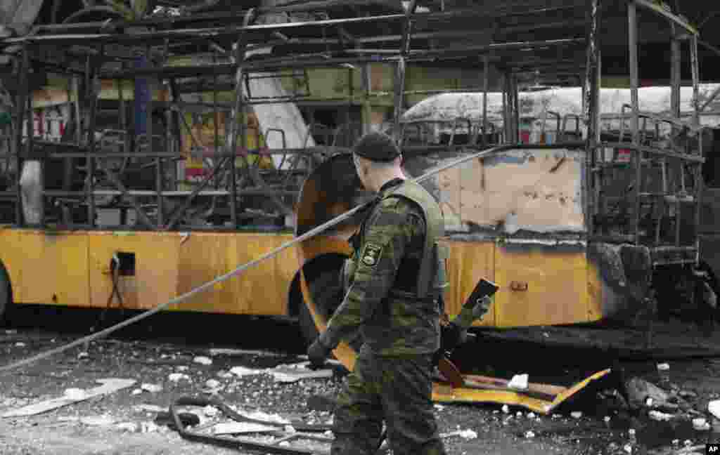 Phiến quân đòi ly khai thân Nga đi ngang qua một trạm xe buýt bị phá hủy sau một vụ pháo kích ở Donetsk, Ukraina, ngày 11/2/2015. 