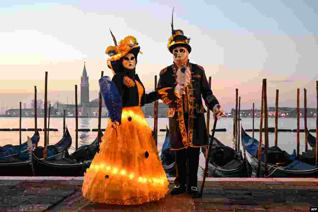 Masked revelers wearing traditional carnival costume pose during the carnival in Venice, Italy.
