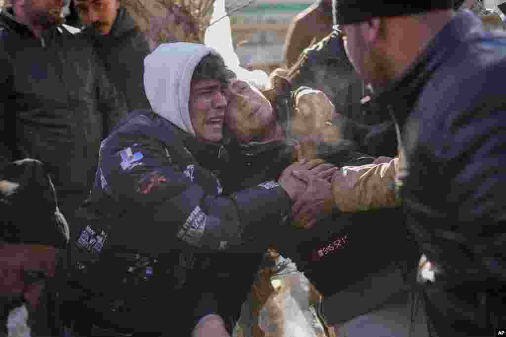 The son of Durmus Kilinc, center, reacts after rescue team members removed the dead body of his father from a destroyed building, in Elbistan, Turkey. Tens of thousands of people who lost their homes in a catastrophic earthquake, huddled around campfires in the bitter cold and clamored for food and water, three days after the temblor hit Turkey and Syria.