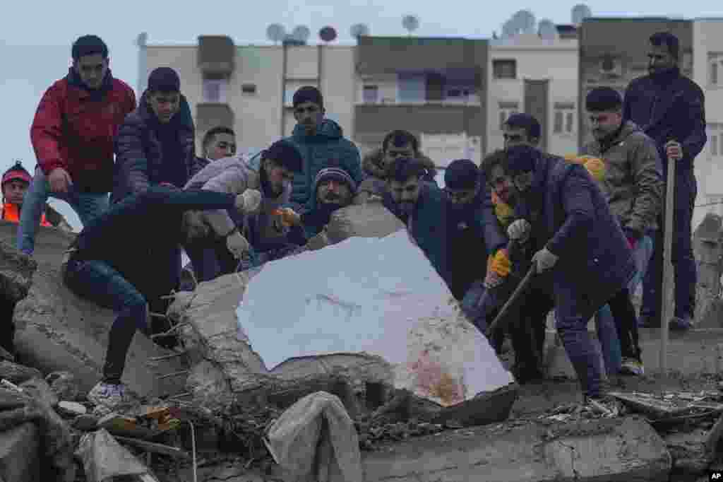 Men search for people among the debris in a destroyed building in Adana, Turkey. A powerful 7.8 magnitude earthquake has rocked wide swaths of Turkey and neighboring Syria, killing more than 2,600 people and injuring thousands more.