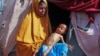 FILE - Boolo Aadan, 63, who fled drought-stricken areas, holds her 9 month old grandchild outside the tent where they now live at a makeshift camp on the outskirts of Mogadishu, Somalia, on Feb. 4, 2022. 