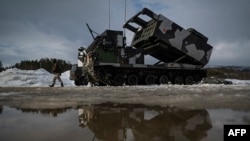 Un soldado pasa junto a un sistema de cohetes de lanzamiento múltiple M270 durante el ejercicio militar internacional Cold Response 22, en Setermoen, Noruega, el 22 de marzo de 2022.